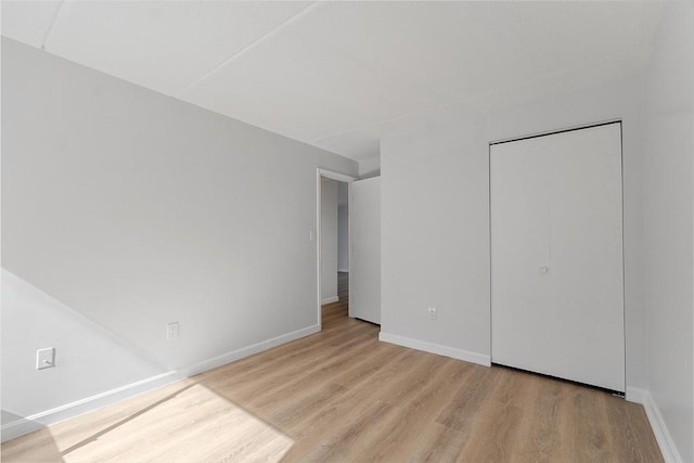 unfurnished bedroom featuring baseboards, a closet, and wood finished floors