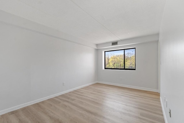 unfurnished room featuring a textured ceiling, baseboards, light wood-style flooring, and visible vents
