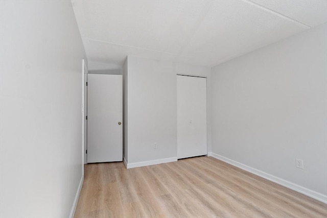 unfurnished bedroom featuring baseboards, a closet, and light wood finished floors