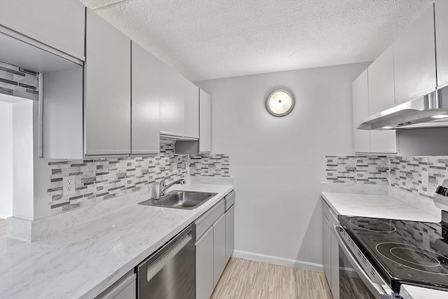 kitchen with a sink, stainless steel appliances, a textured ceiling, and under cabinet range hood