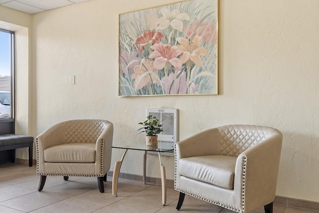 sitting room featuring baseboards, heating unit, and a textured wall
