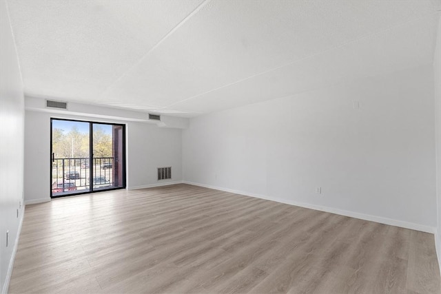 spare room featuring baseboards, light wood-style flooring, and visible vents