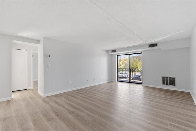 unfurnished living room with visible vents, baseboards, and light wood-type flooring