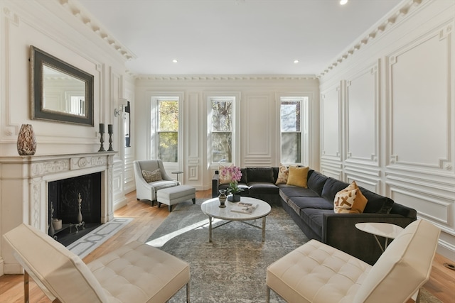 living room with crown molding, a high end fireplace, light hardwood / wood-style floors, and plenty of natural light