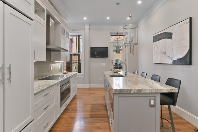 kitchen featuring stainless steel oven, an island with sink, a kitchen breakfast bar, and white cabinets