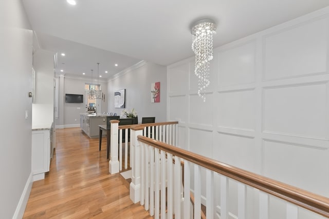 hall with ornamental molding, light hardwood / wood-style flooring, and a chandelier