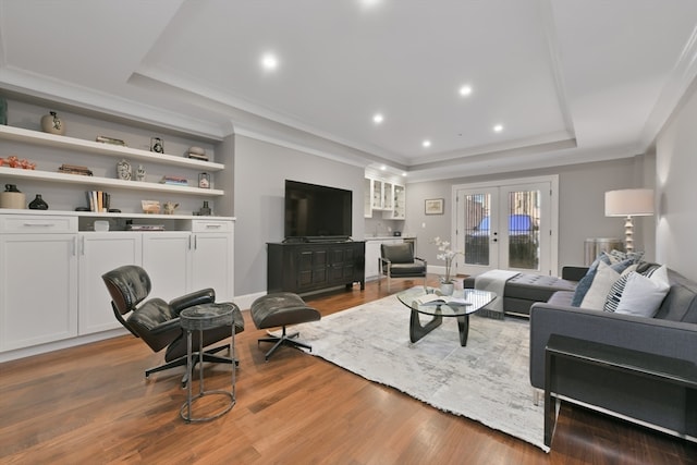 living room featuring ornamental molding, french doors, hardwood / wood-style flooring, and a tray ceiling