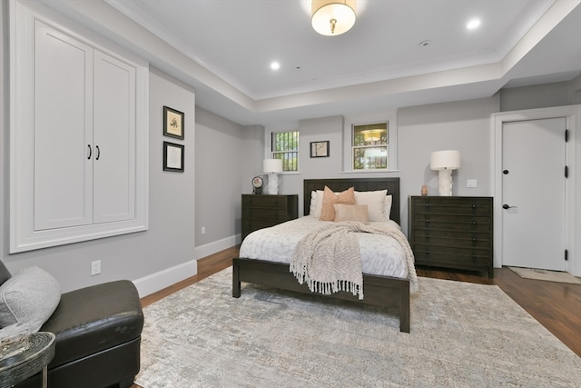 bedroom with dark hardwood / wood-style flooring and a tray ceiling