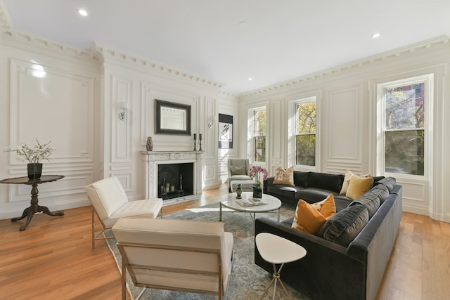 living room with a premium fireplace, light hardwood / wood-style floors, and crown molding