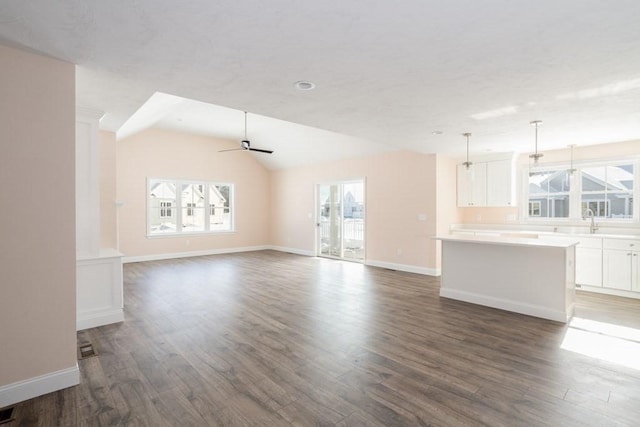 unfurnished living room with dark wood-type flooring, ceiling fan, and vaulted ceiling