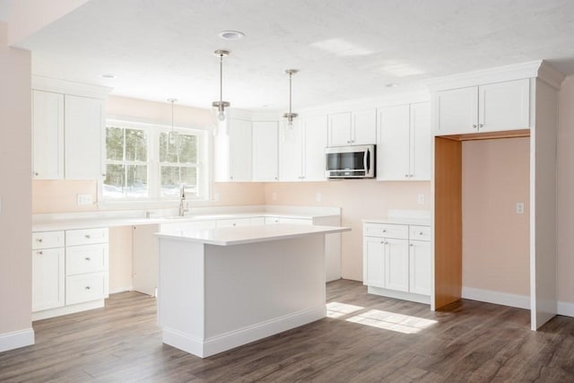 kitchen featuring decorative light fixtures, wood-type flooring, white cabinets, and a kitchen island