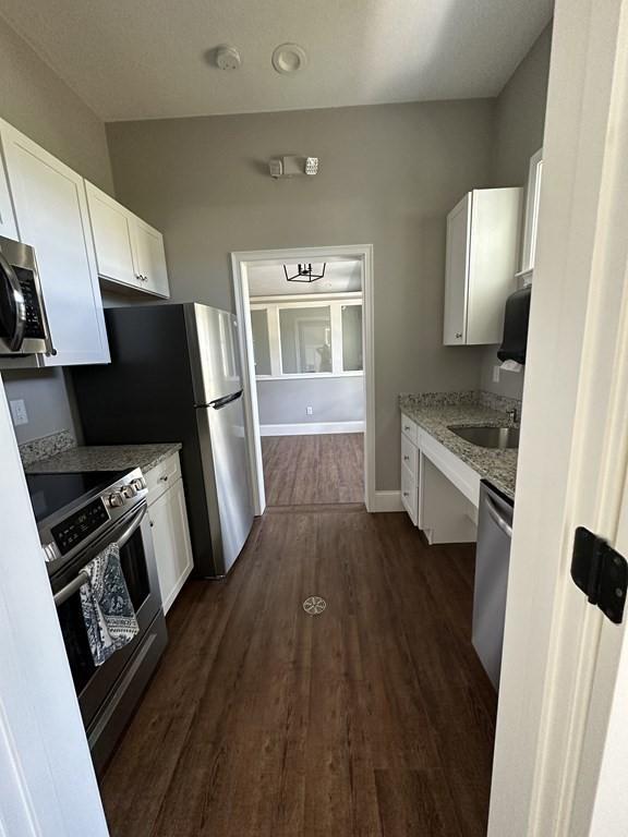 kitchen with white cabinets, dark hardwood / wood-style flooring, appliances with stainless steel finishes, and sink