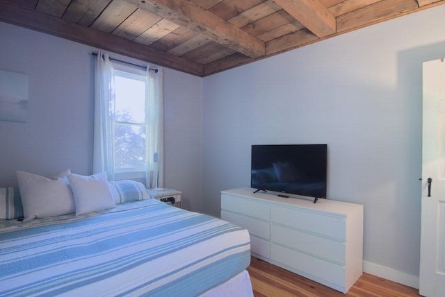 bedroom with baseboards, beamed ceiling, wooden ceiling, and light wood-style floors