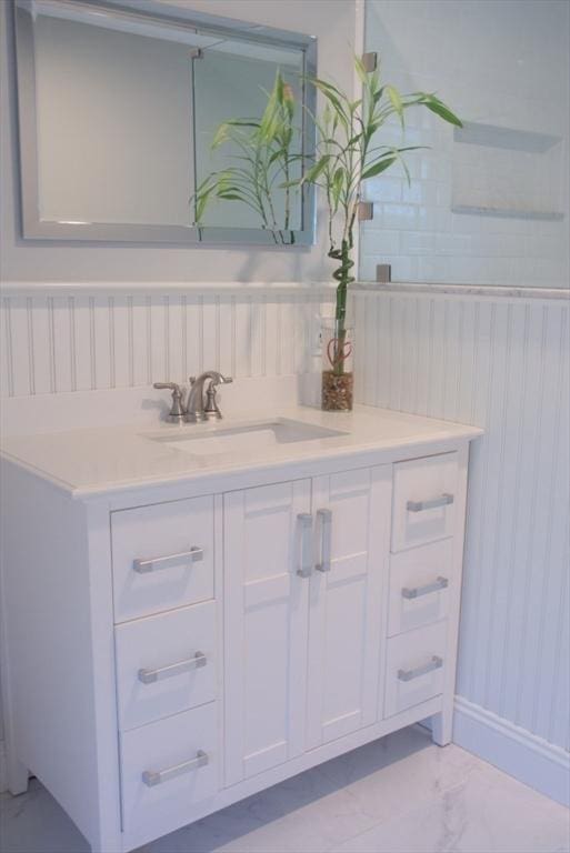 bathroom with marble finish floor, vanity, and baseboards