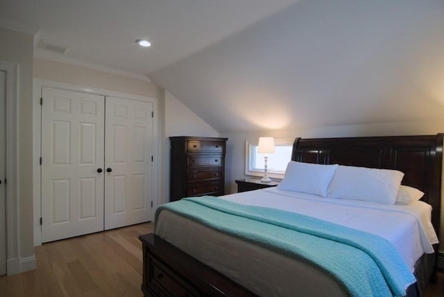 bedroom with vaulted ceiling, a closet, wood finished floors, and recessed lighting