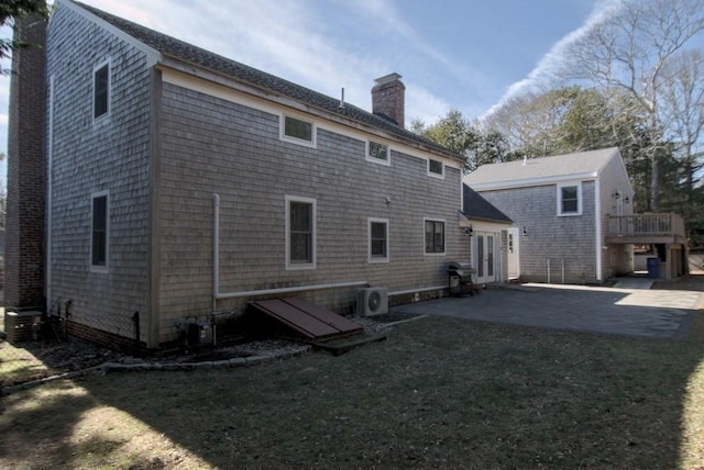 rear view of property featuring a patio, ac unit, french doors, a lawn, and a chimney