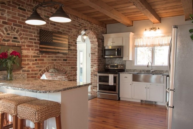 kitchen featuring white cabinets, wood ceiling, stainless steel appliances, and a sink