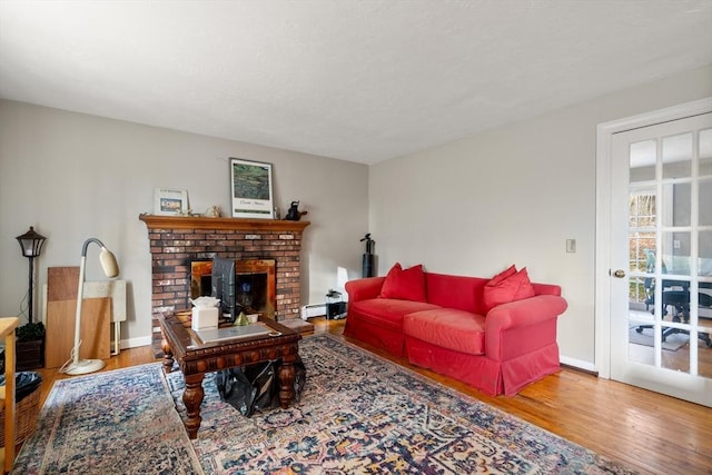 living room with baseboard heating, hardwood / wood-style floors, and a fireplace