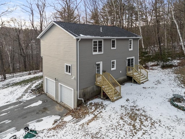 snow covered rear of property featuring a garage