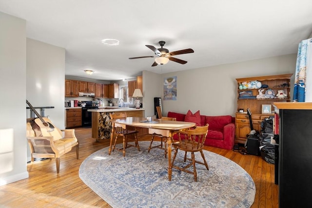 dining space featuring ceiling fan, light hardwood / wood-style flooring, and sink