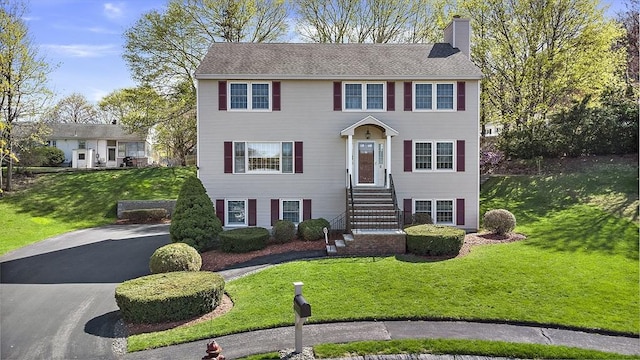 colonial inspired home featuring a front lawn and a chimney