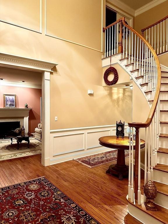 6 Everett Cir, Hopkinton, MA 01748 - stairway featuring a decorative wall, a fireplace, ornamental molding, wood finished floors, and wainscoting