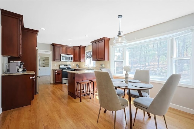 dining room with light wood finished floors, recessed lighting, and baseboards