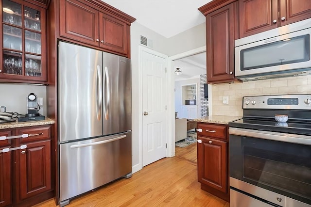 kitchen featuring tasteful backsplash, visible vents, light stone countertops, light wood-style flooring, and stainless steel appliances