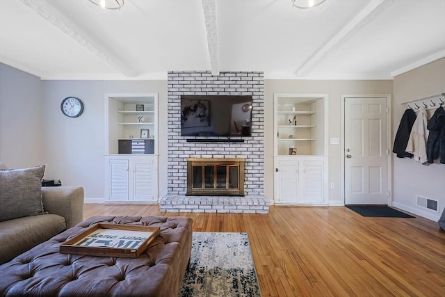 living room with beam ceiling, built in features, and baseboards