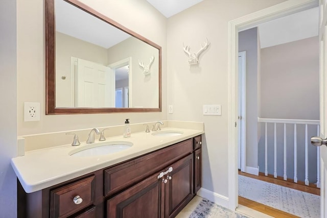 bathroom featuring a sink, baseboards, and double vanity