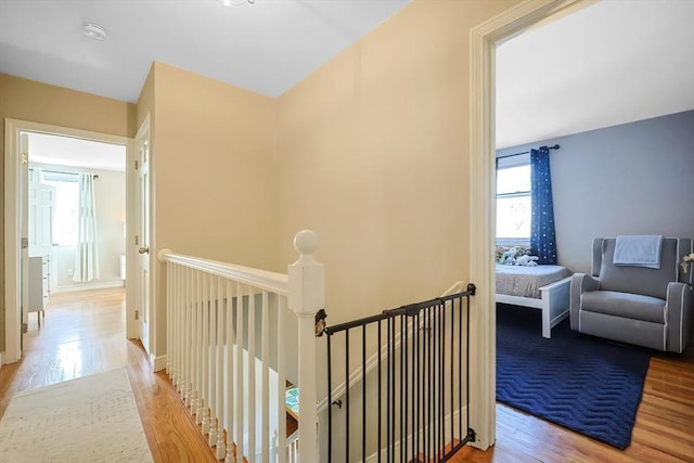 hallway with an upstairs landing, baseboards, and wood finished floors