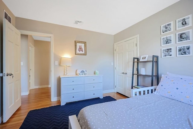 bedroom featuring visible vents, baseboards, and wood finished floors