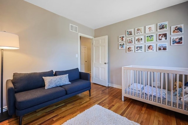 bedroom featuring visible vents, baseboards, and wood finished floors