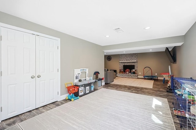 game room with a brick fireplace, recessed lighting, wood finished floors, and baseboards