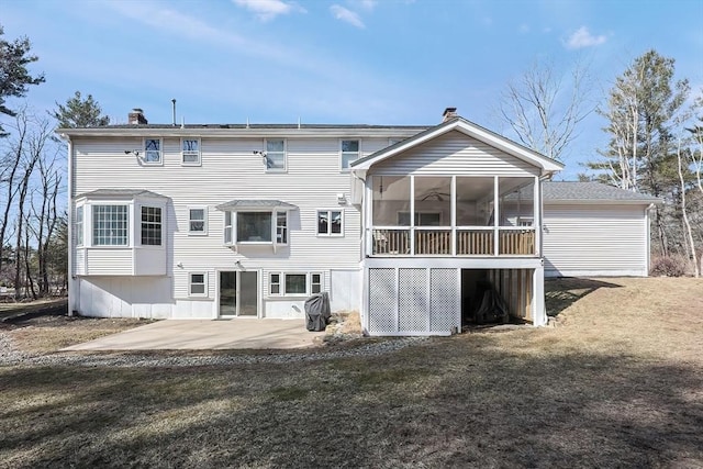 back of property with a yard, a sunroom, a chimney, and a patio area