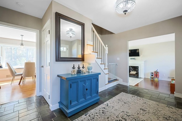 corridor with visible vents, baseboards, stone tile flooring, and stairs