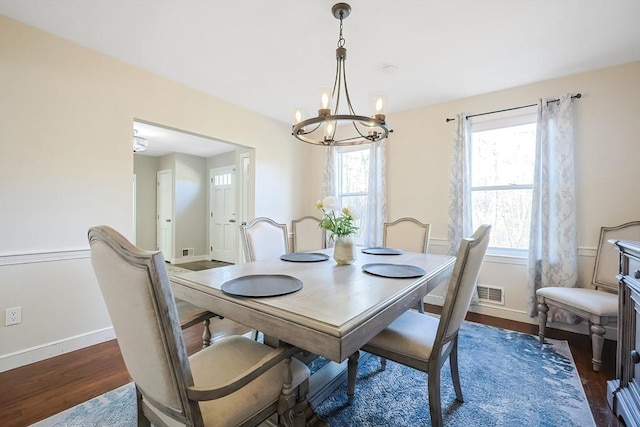 dining room featuring a wealth of natural light, a notable chandelier, baseboards, and wood finished floors