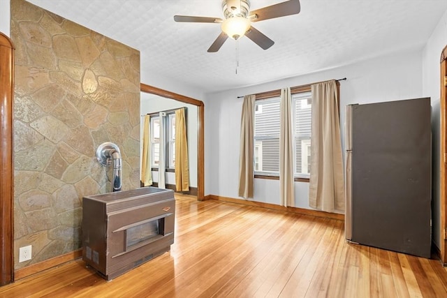 570 William St, Fall River, MA 02721 - unfurnished living room featuring a wood stove, light wood finished floors, baseboards, and ceiling fan