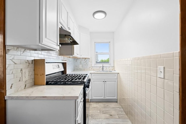 570 William St, Fall River, MA 02721 - kitchen with under cabinet range hood, gas range, a sink, light wood finished floors, and white cabinets