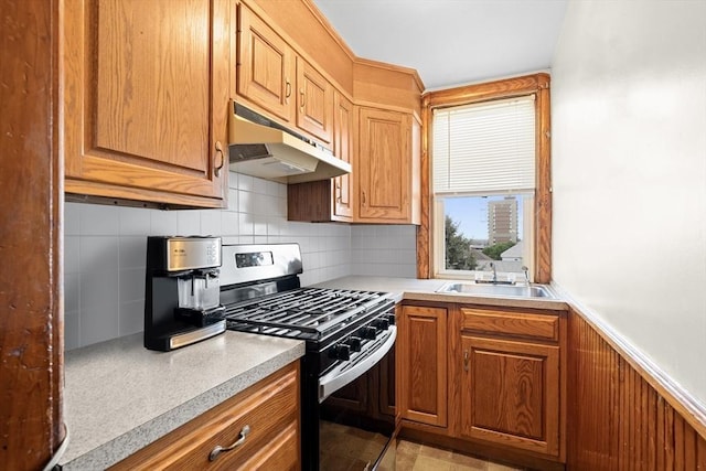 570 William St, Fall River, MA 02721 - kitchen with gas range, under cabinet range hood, a sink, decorative backsplash, and light countertops