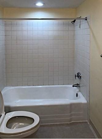 bathroom with tiled shower / bath, tile patterned floors, and toilet