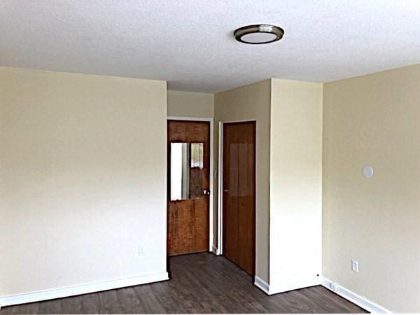 unfurnished room with dark hardwood / wood-style floors and a textured ceiling