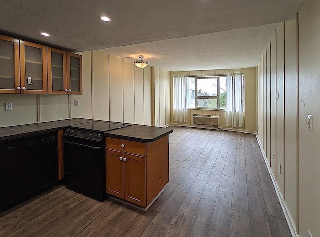 kitchen with a wall mounted air conditioner, black appliances, dark hardwood / wood-style floors, and kitchen peninsula