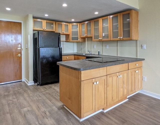 kitchen featuring sink, wood-type flooring, black appliances, and kitchen peninsula