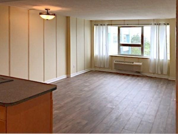 empty room with a wall unit AC and dark hardwood / wood-style flooring