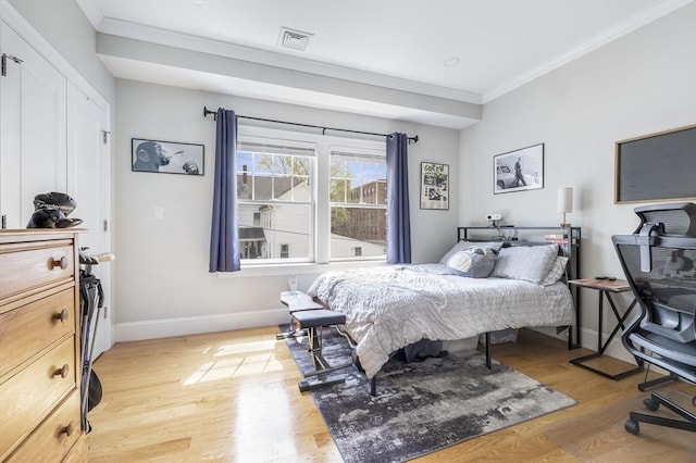 bedroom with crown molding, baseboards, visible vents, and light wood-type flooring