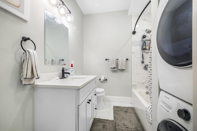 full bathroom with vanity, toilet, baseboards, stacked washing maching and dryer, and tile patterned floors