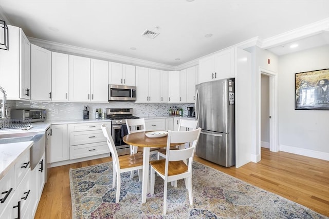 kitchen featuring white cabinets, appliances with stainless steel finishes, decorative backsplash, and visible vents