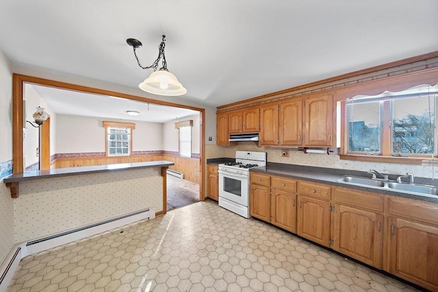 kitchen with decorative light fixtures, wood walls, sink, white range with gas cooktop, and a baseboard radiator