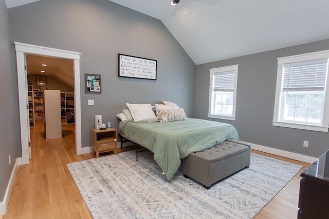 bedroom featuring light wood-style flooring, baseboards, lofted ceiling, and a ceiling fan